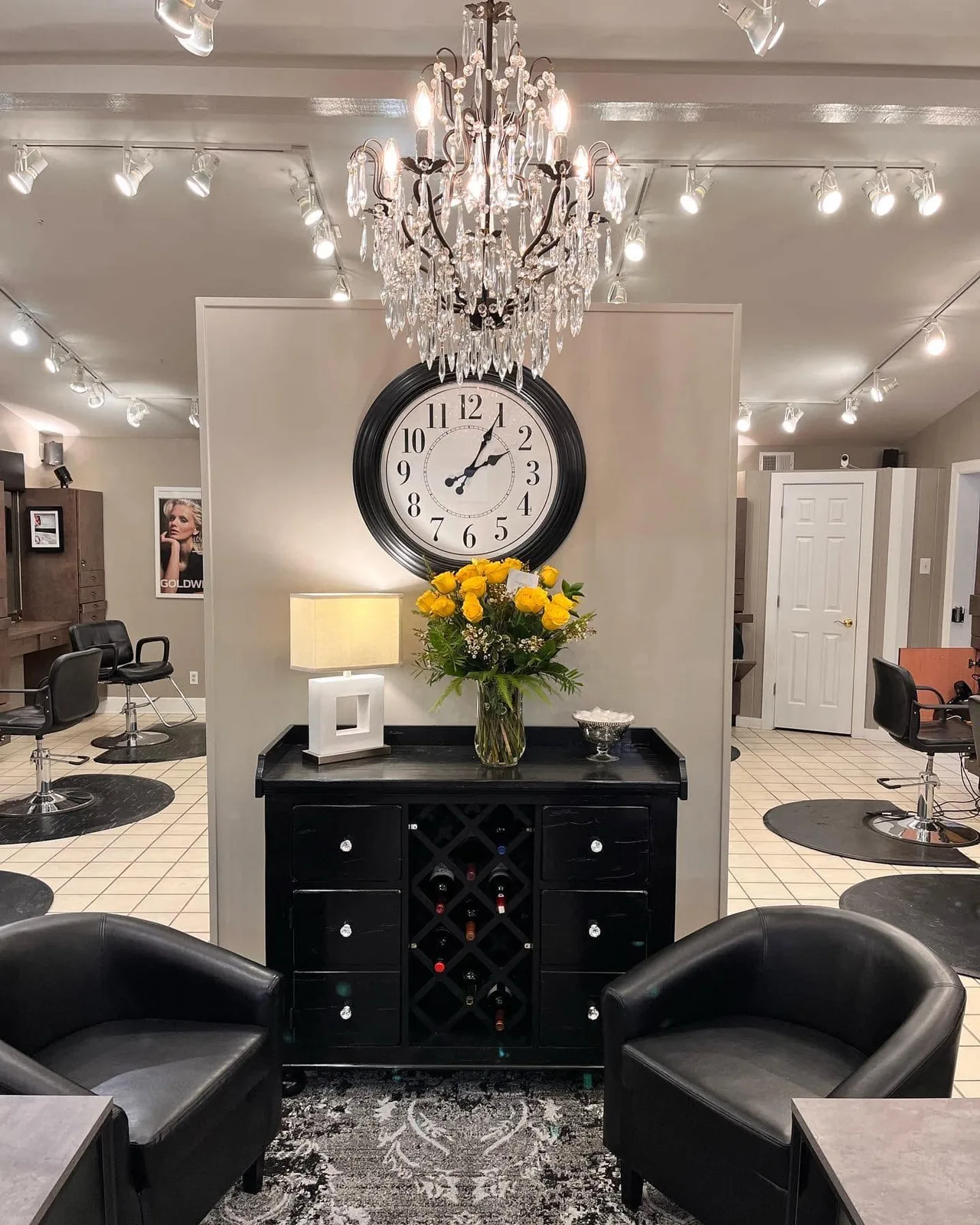 The front lounge, with a chandelier, a wall clock and black armchairs