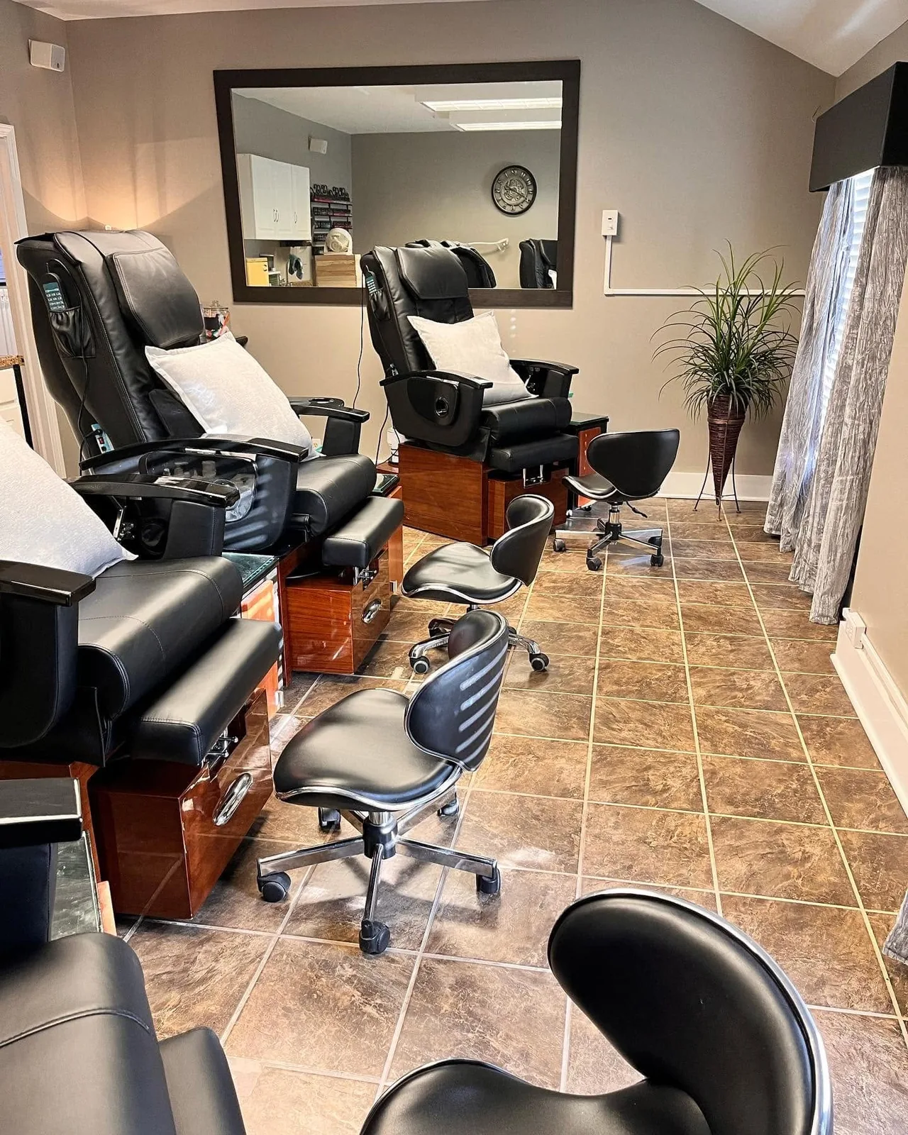 Black pedicure chairs facing a large mirror