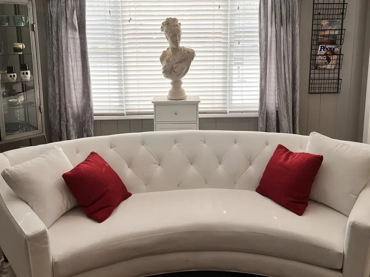 The waiting area: a white curved sofa with red pillows under the front window