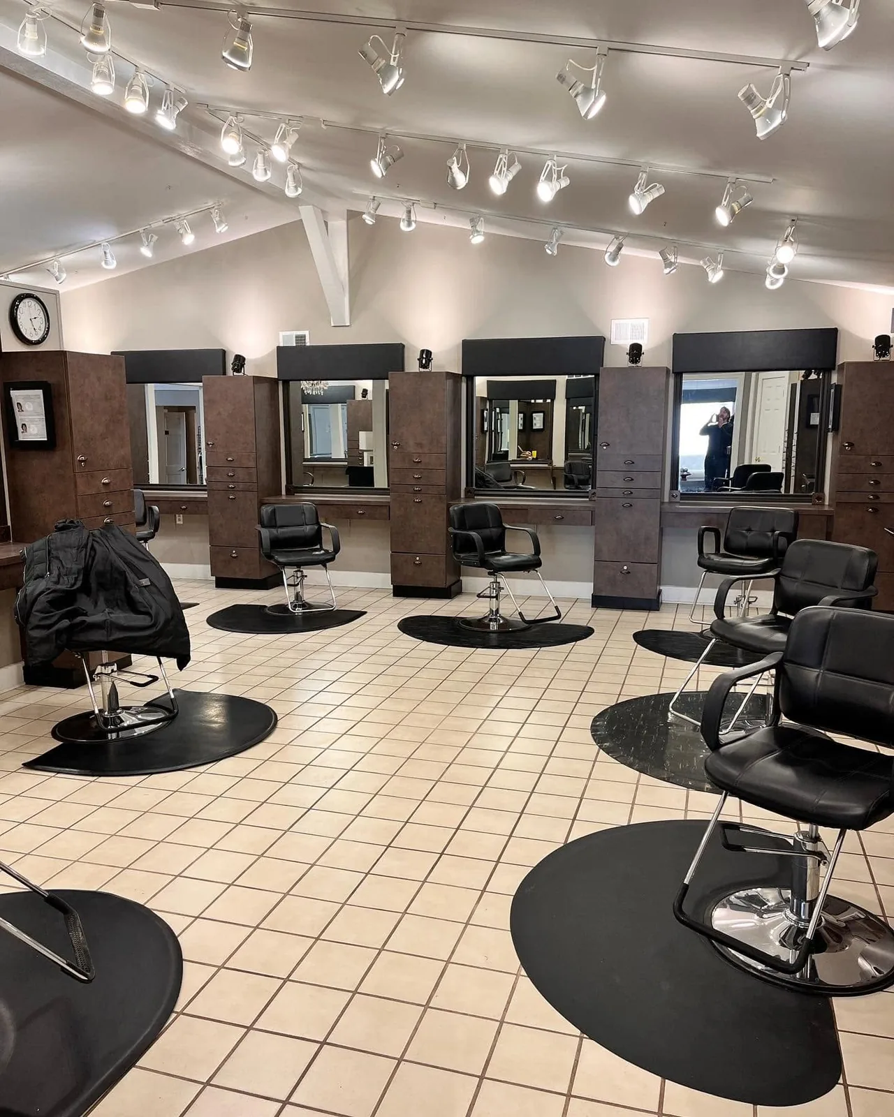 The styling floor: black styling chairs at a row of mirrors under track lights